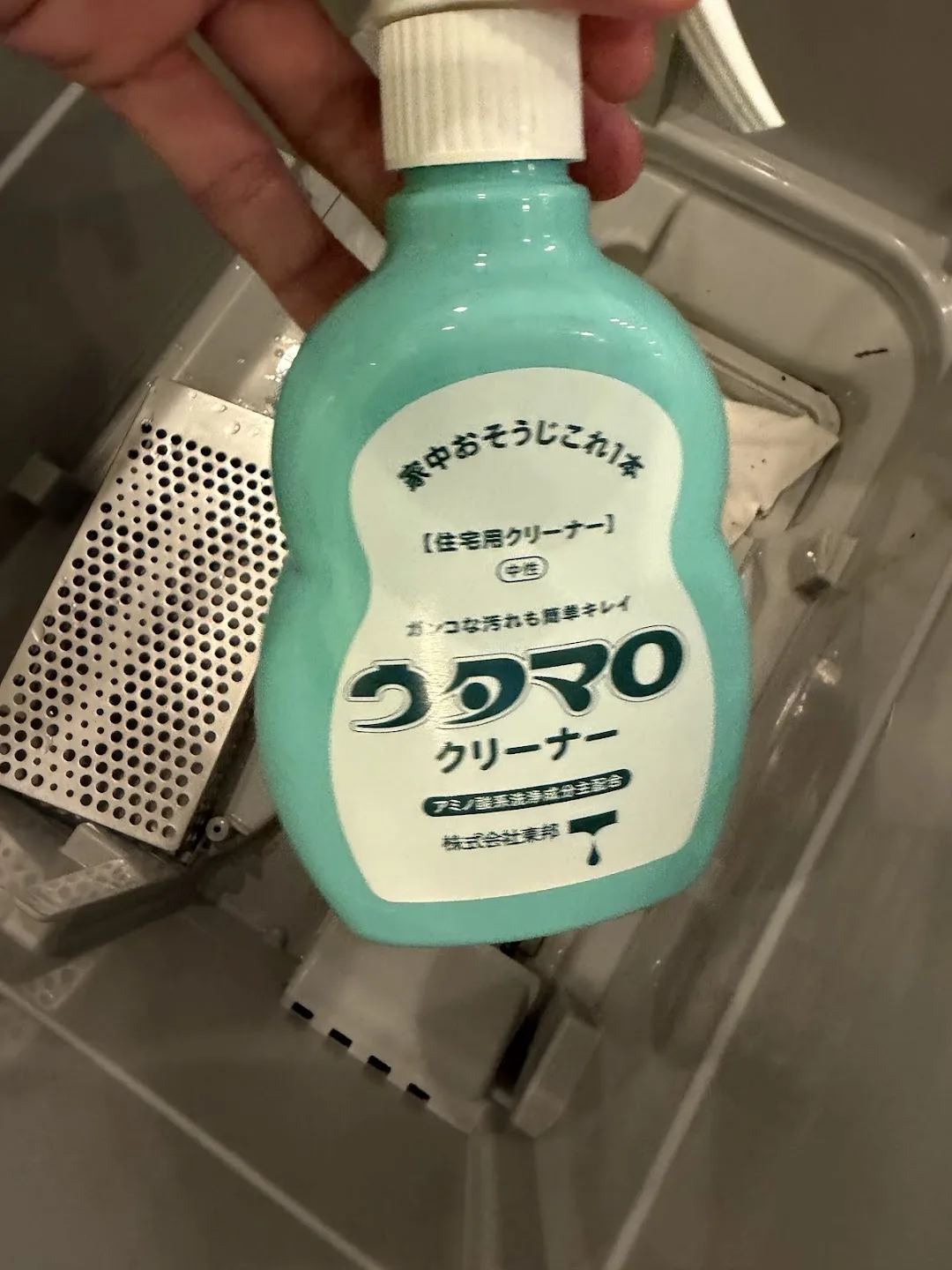 食洗機の庫内でウタマロクリーナー(住宅用・中性)のボトルを手に持っている