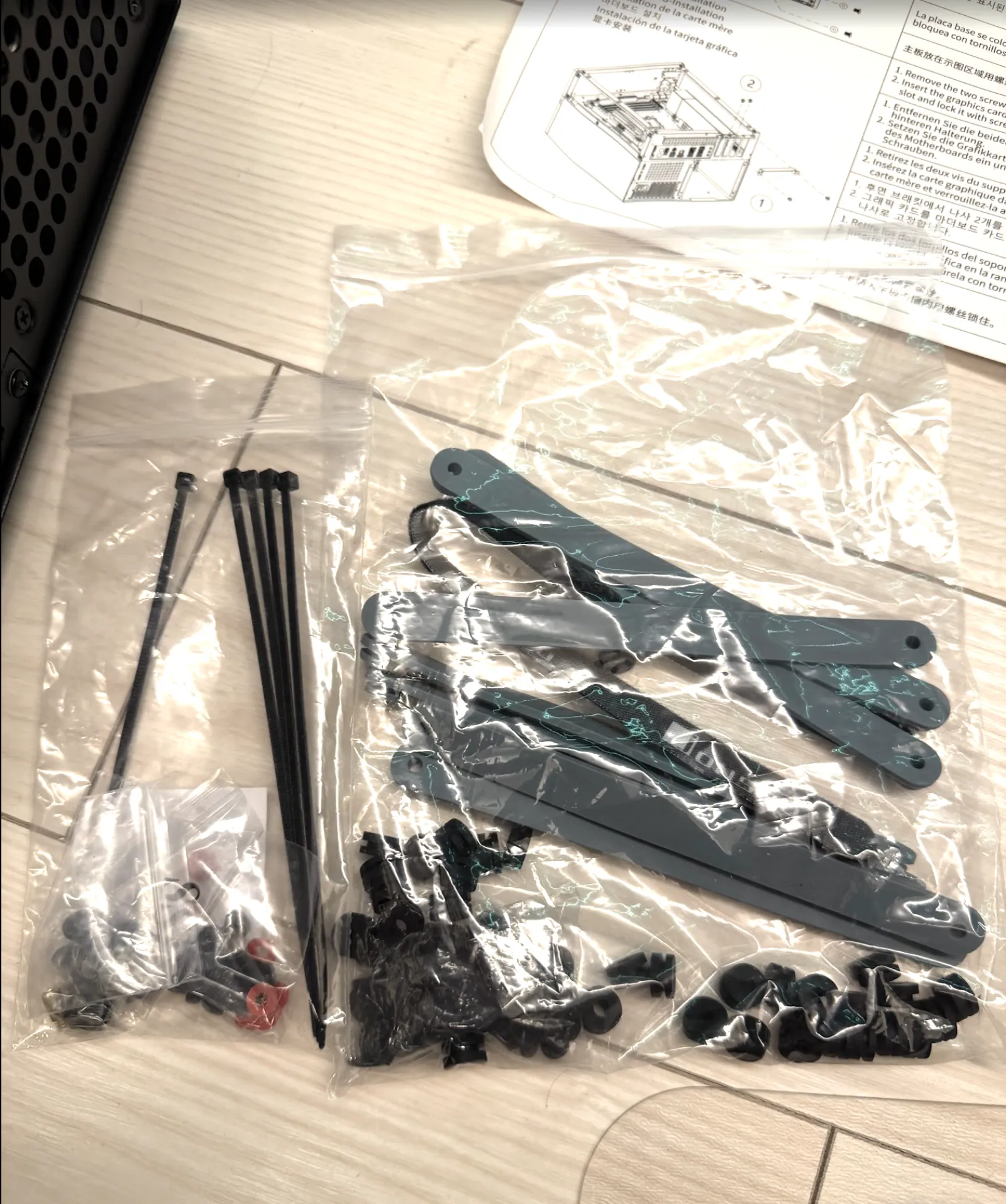 JONSBO N4 の付属品。結束バンド、ネジ、HDD 用のゴムグロメットとグレーのハンドル