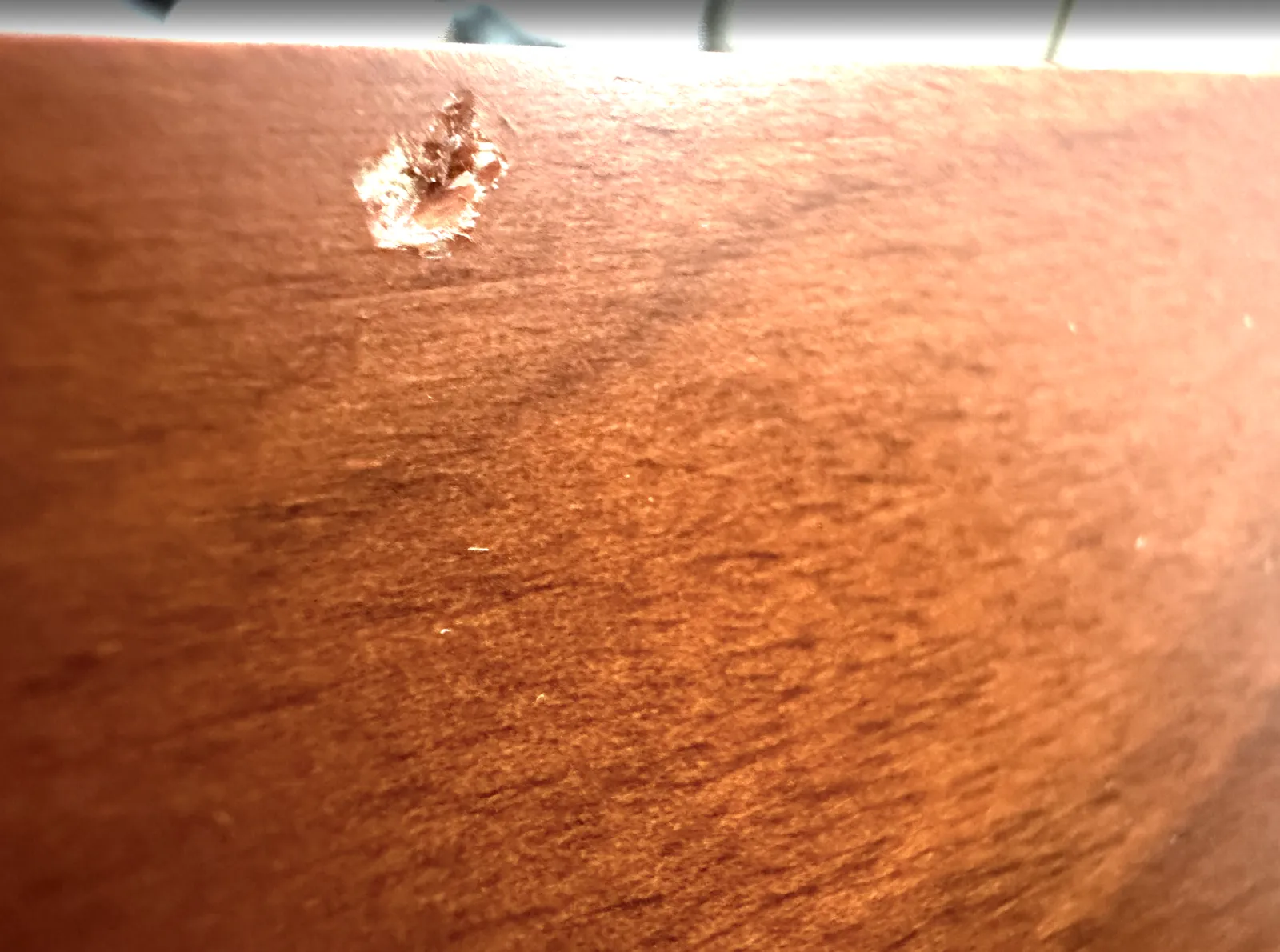 木目パネルの角にできた欠け。塗装が剥げて下地が見えている